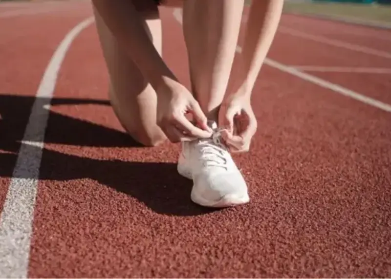 Runner tieing their laces on a running track