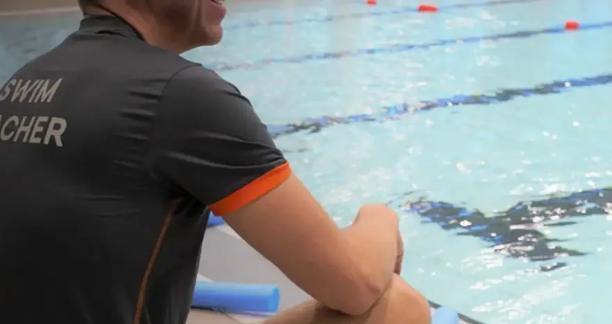 Swimming teacher sat on poolside