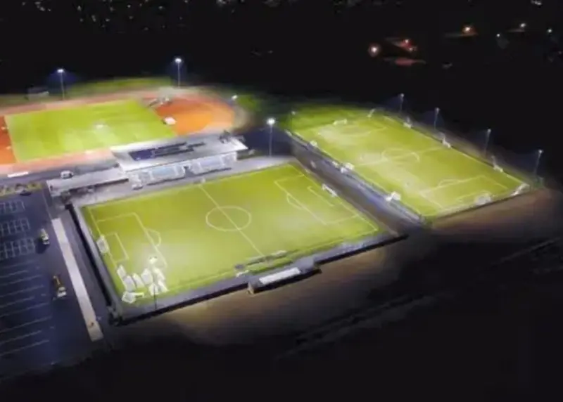 Night time aerial view of two football pitches and athletics stadium