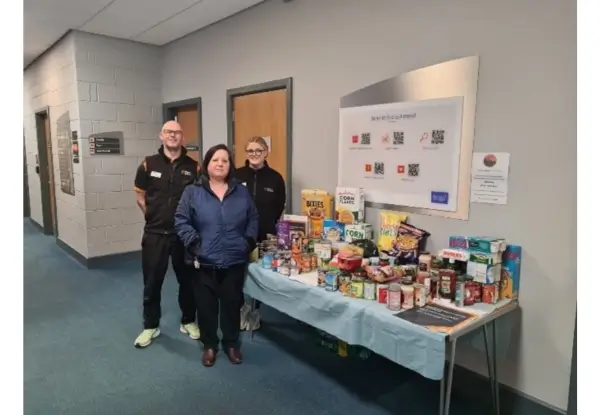 Staff standing in front of bench with food donations